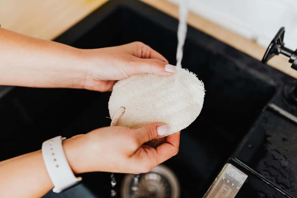 person washing something in a sink - Why Does My Sink Smell? Figure Out Why