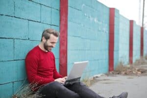 man leaning against a wall using a laptop 300x200 - man leaning against a wall using a laptop