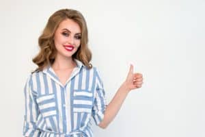 cheerful young woman in a blue striped shirt giving a thumbs up against a plain background 300x200 - cheerful young woman in a blue striped shirt giving a thumbs up against a plain background..jpg