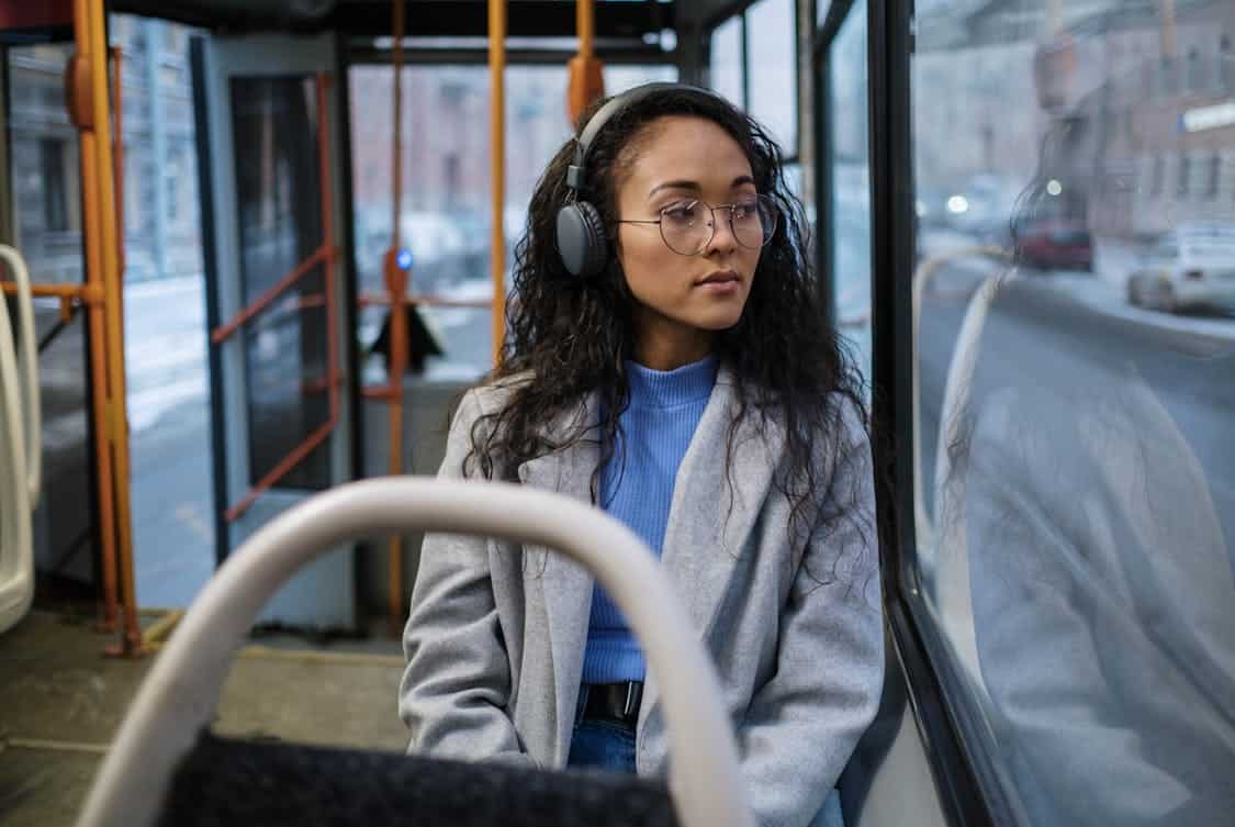 A Woman Riding a Bus Wearing Headphones - How to Reduce Commuting Stress Using Shuttle Buses