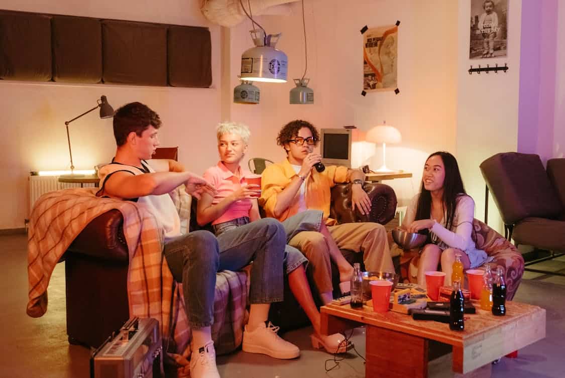a group of friends sitting on a sofa while watching tv - 5 Long-Term Benefits of Installing Epoxy in Your Basement